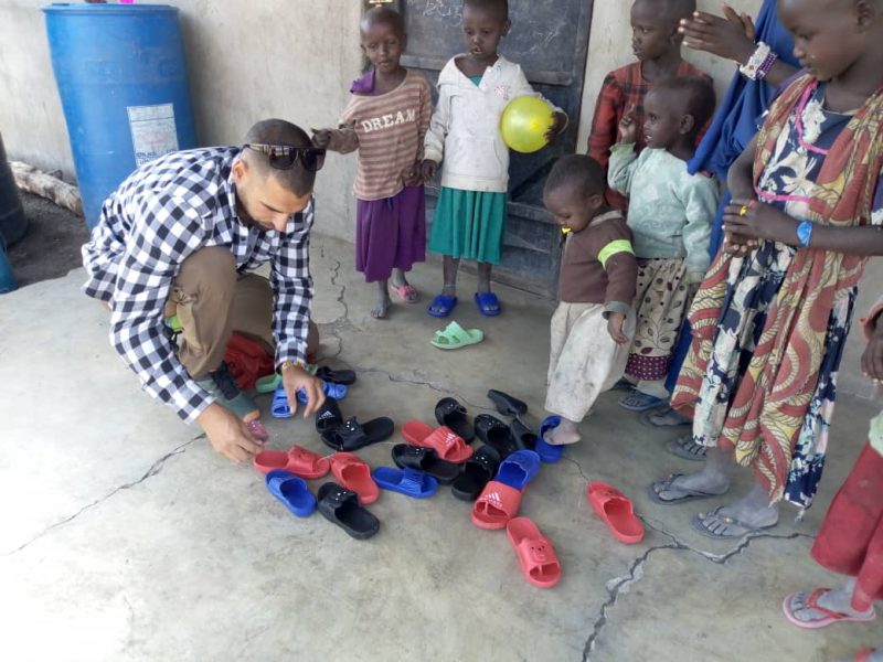volunter giving new shoes to children on teaching project
