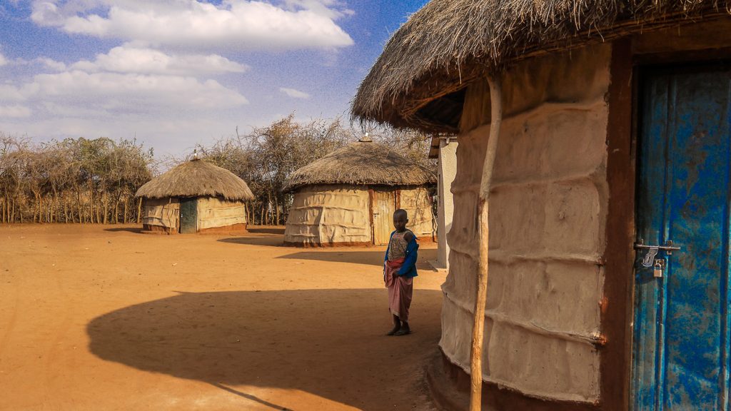 child by mud huts in Tanzania