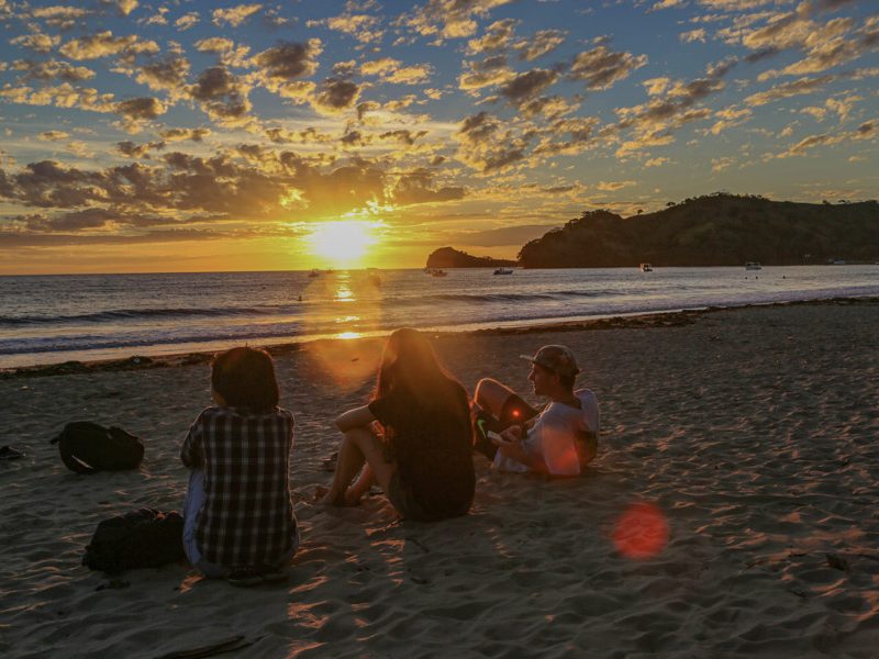 group sitting on the beach at sunset